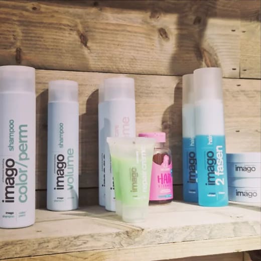 Flessen en tubes van Imago op een houten plank in de salon.