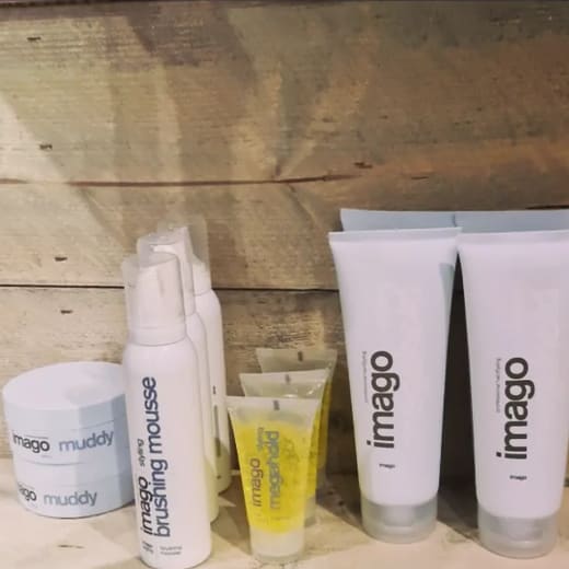Stylingproducten van Imago op een houten plank: potjes Muddy, brushing mousse, Megahold-gel en tubes.