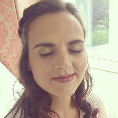 Bruid met natuurlijke make-up en losse krullen, ogen gesloten.