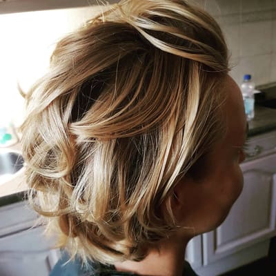 Kort blond haar met highlights, volume en golven.