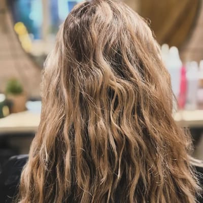 Voor: lang, golvend blond haar, van achteren gezien.